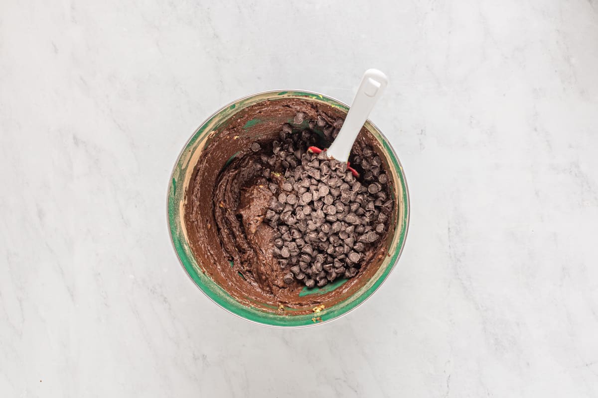 chocolate chips folded into avocado brownie batter with a rubber spatula.