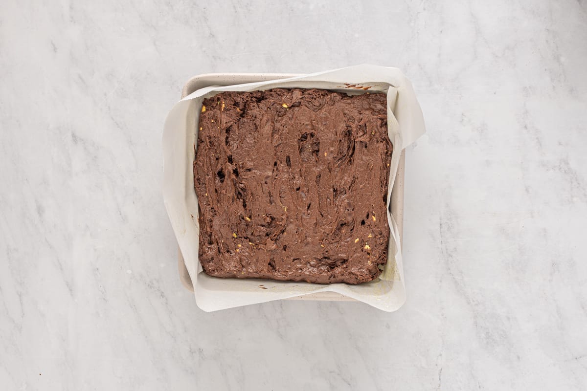 avocado brownie batter spread into a square baking pan.