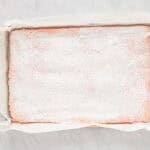 baked strawberry cake dusted with powdered sugar in a cake pan.