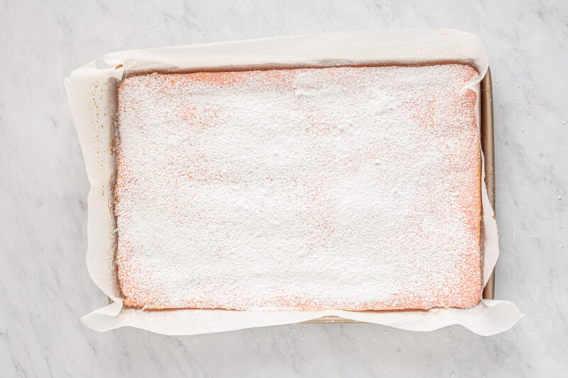 baked strawberry cake dusted with powdered sugar in a cake pan.