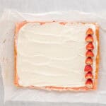 strawberry cake covered with cream cheese filling and a thin line of strawberries on the far right side.