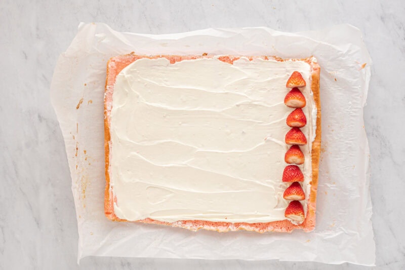 strawberry cake covered with cream cheese filling and a thin line of strawberries on the far right side.