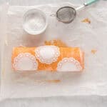 three paper doilies placed on top of strawberry roll cake.