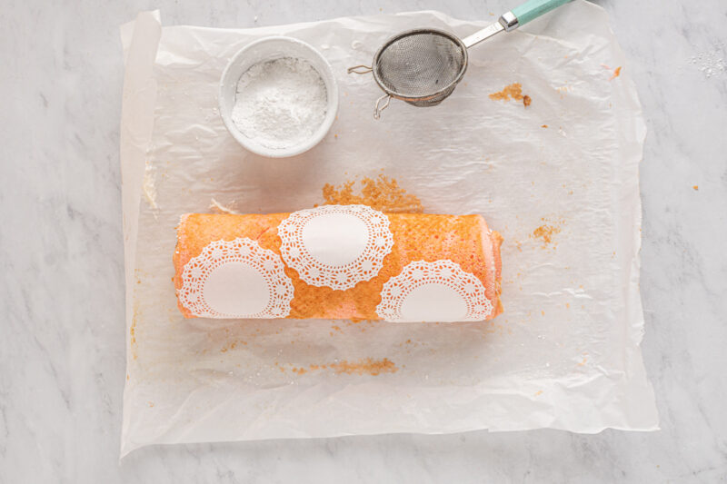 three paper doilies placed on top of strawberry roll cake.