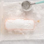 strawberry roll cake topped with paper doilies, covered in powdered sugar.