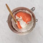 folding strawberry egg yolk mixture into egg white meringue in a mixing bowl with a rubber spatula.