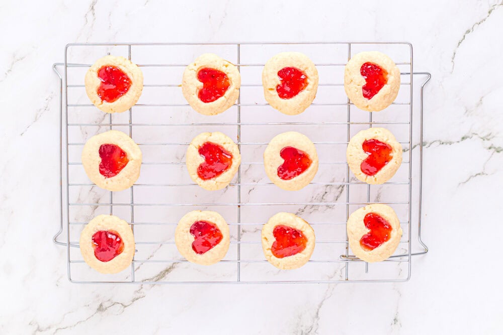 12 heart thumbprint cookies on a wire cooling rack.