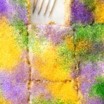 close up view of sliced king cake poke cake with a slice missing and a fork.