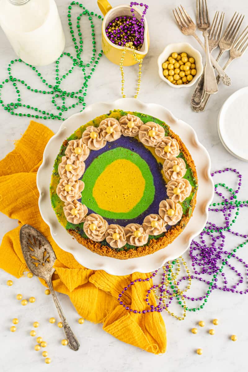 overhead view of king cake cheesecake on a white cake stand.