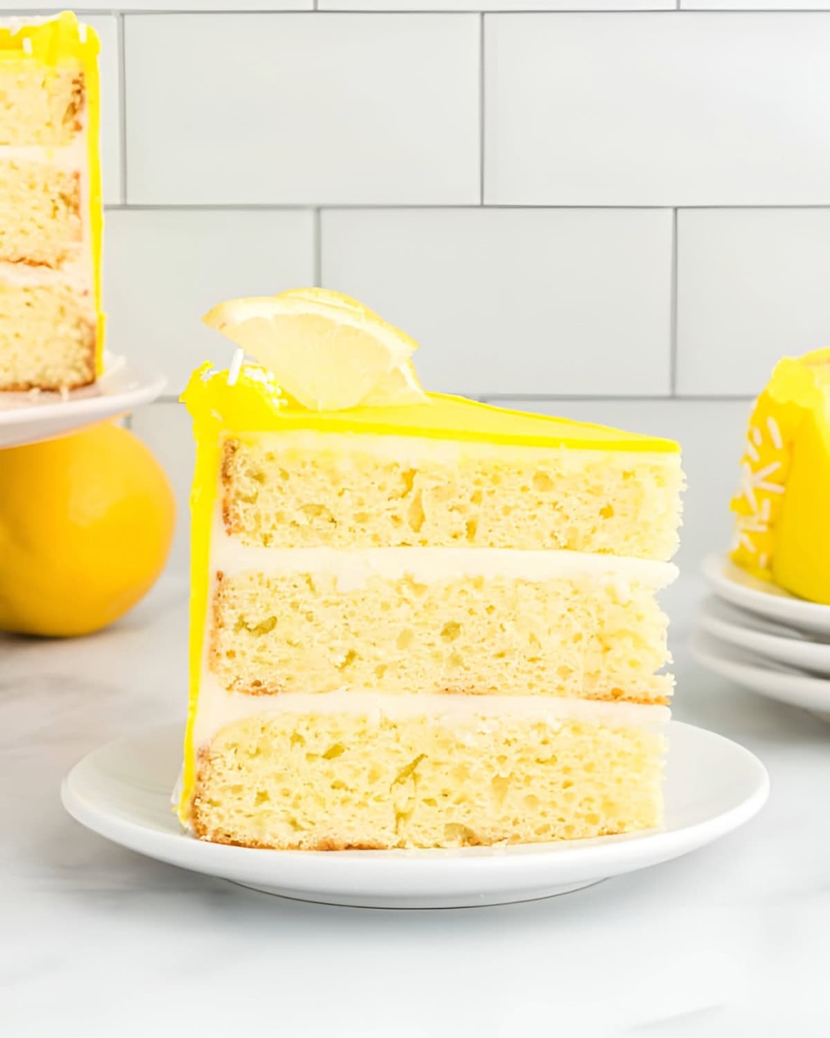 a slice of three-tier moist lemon cake on a white plate.