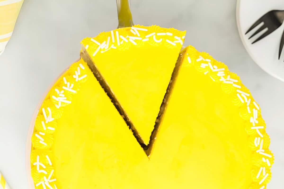 removing a slice of moist lemon cake with a cake server.