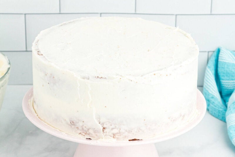 crumb-coated lemon cake on a pink cake stand.