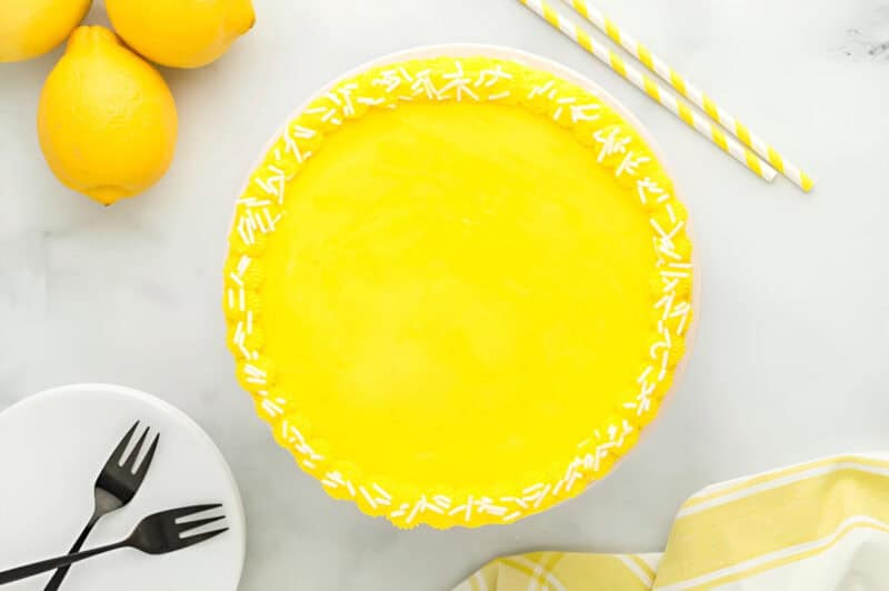 frosted lemon cake with sprinkles on a cake stand.