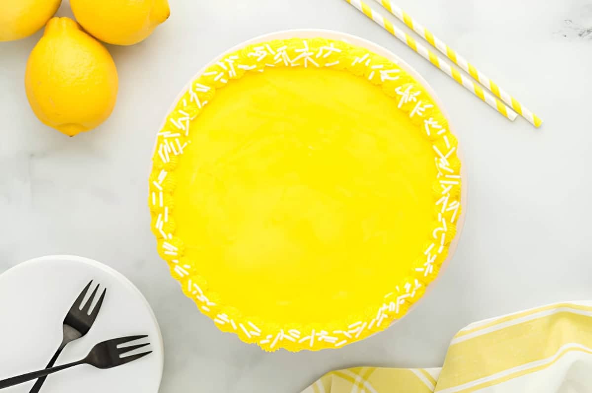 frosted lemon cake with sprinkles on a cake stand.