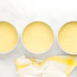 lemon cake batter divided between three round cake pans.