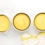three baked lemon cake layers in round cake pans.