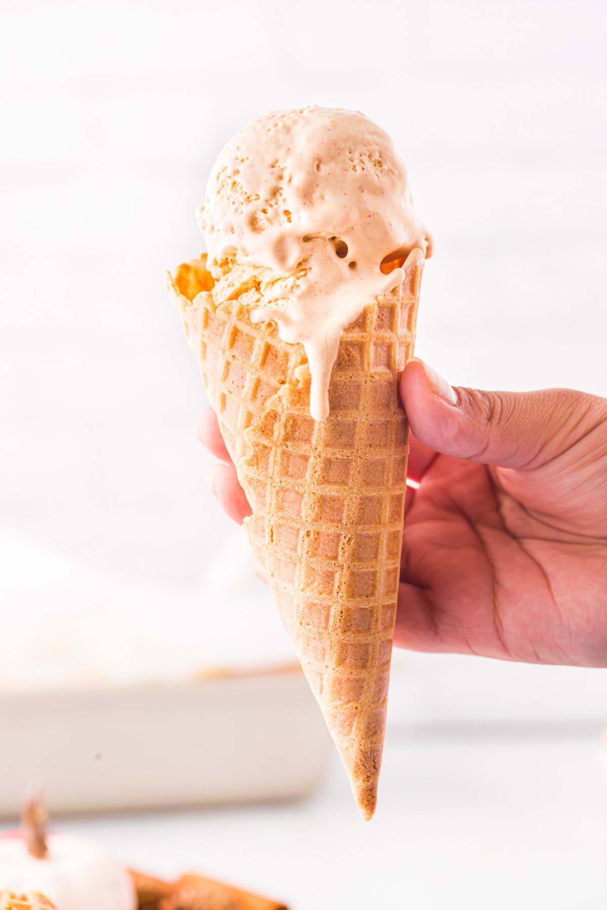 hand holding a waffle cone filled with pumpkin ice cream