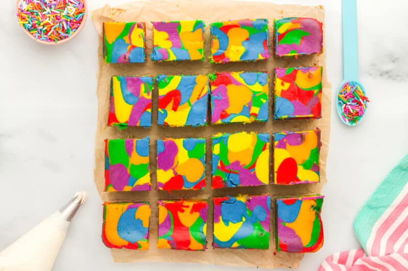 overhead view of cut rainbow cheesecake bars on parchment.