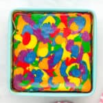 baked rainbow cheesecake in a lined square baking pan.