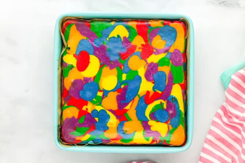 baked rainbow cheesecake in a lined square baking pan.