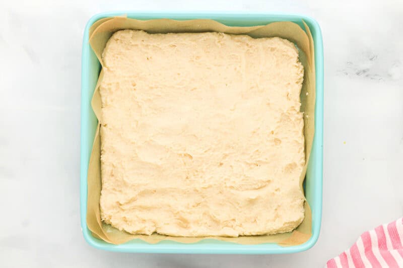 shortbread cookie crust pressed into a lined square baking pan.
