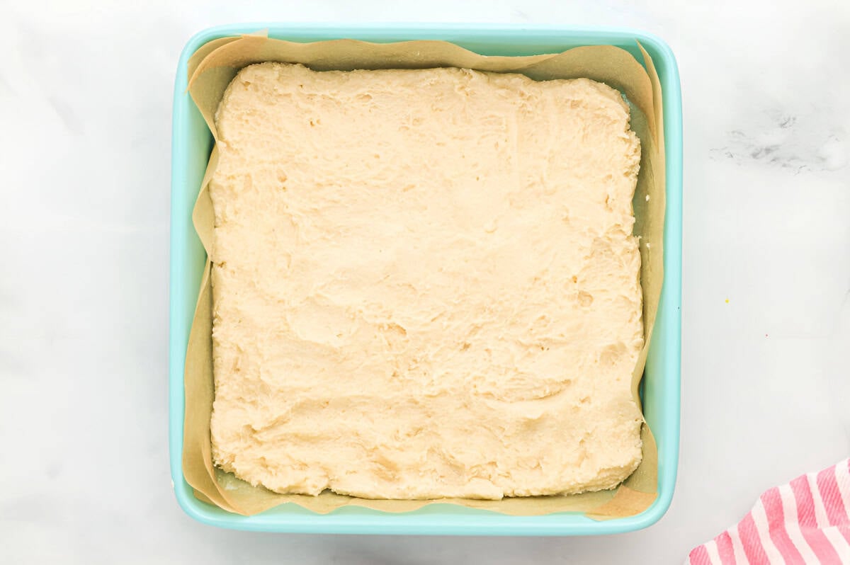 shortbread cookie crust pressed into a lined square baking pan.