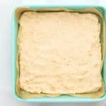 docked shortbread cookie crust in a lined square baking pan before baking.