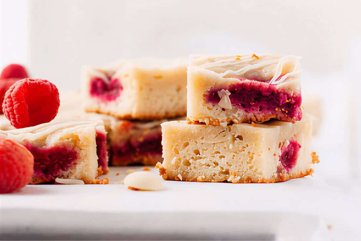side view of stacks of raspberry white chocolate blondies on a marble platter.