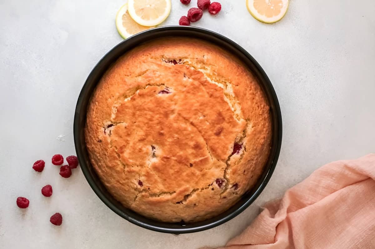 baked raspberry olive oil cake in a round cake pan.