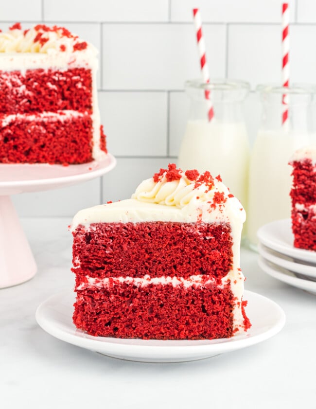side view of a slice of red velvet cake on a white plate.