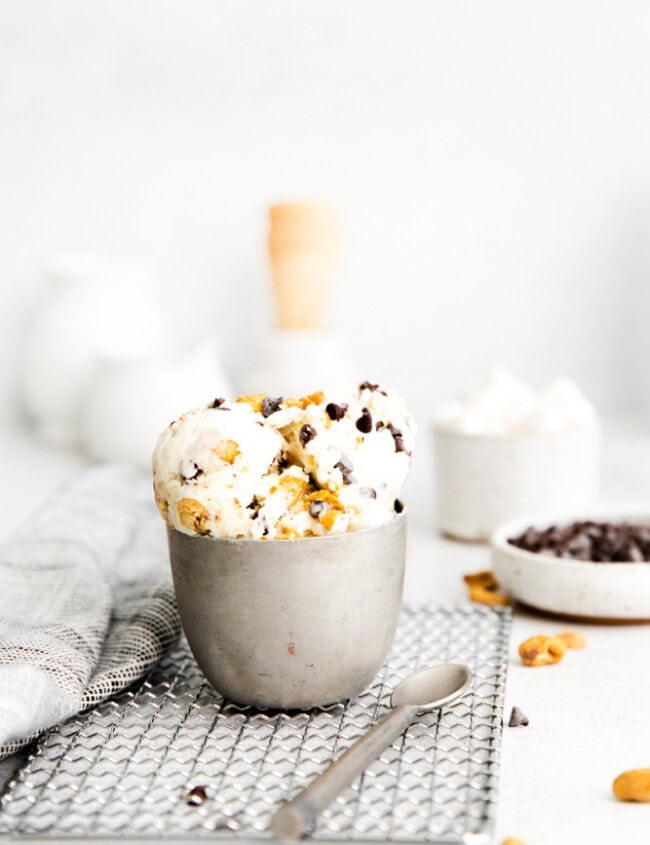 side view of a serving of no churn rocky road ice cream in a silver cup on a wire rack.