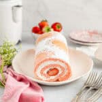 three-quarters view of strawberry roll cake showing the cream and strawberry filling.