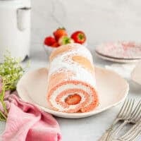 three-quarters view of strawberry roll cake showing the cream and strawberry filling.