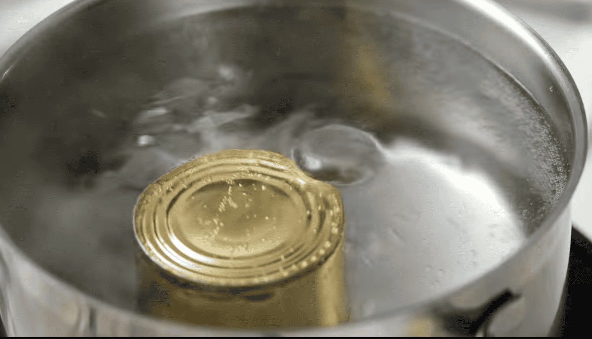 boiling a can of sweetened condensed milk in a large pot.