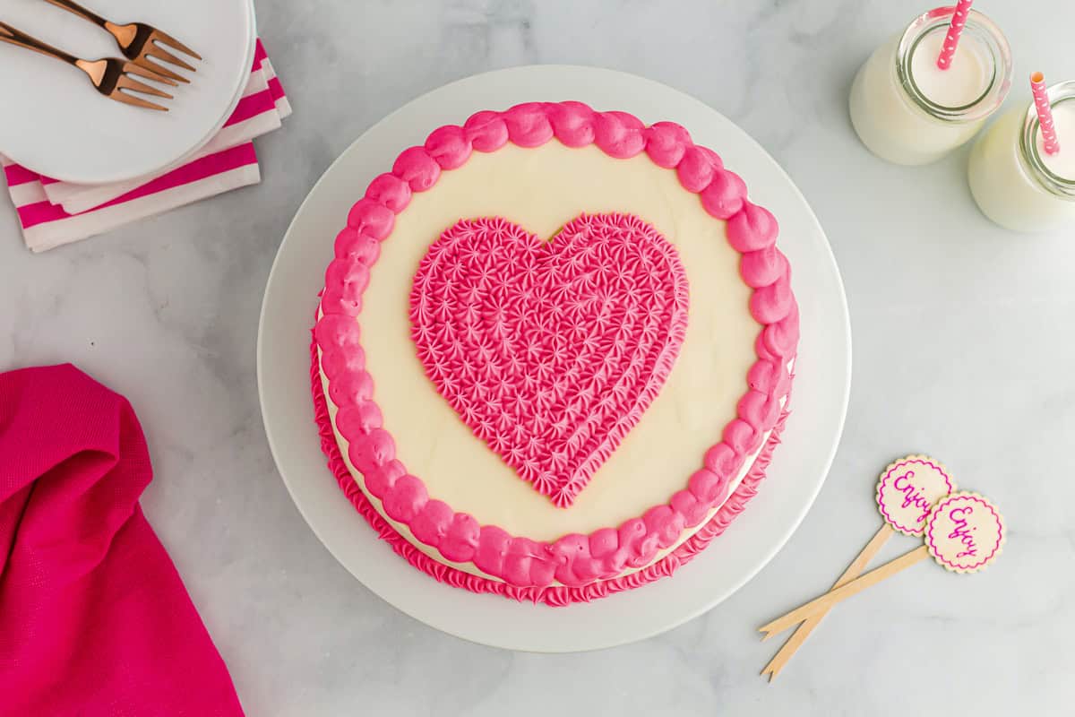 overhead view of a pink velvet cake with a pink frosted heart on top.