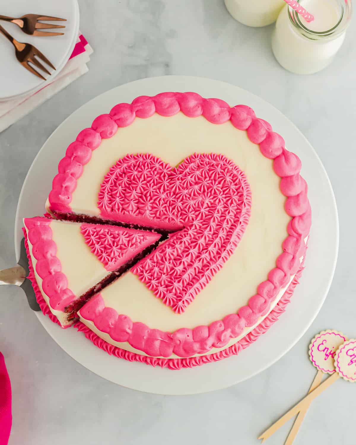 removing a slice of pink velvet cake from a whole cake with a cake server.