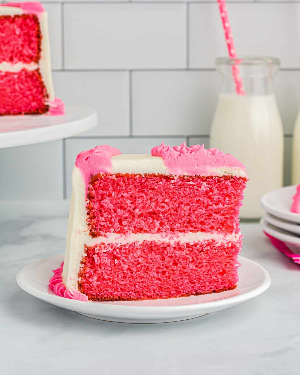 side view of a slice of pink velvet cake on a white plate.