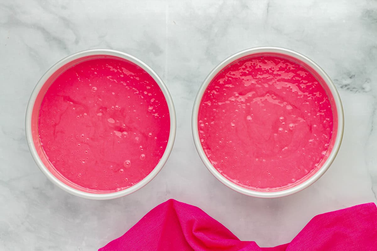 pink cake batter in 2 round cake pans.