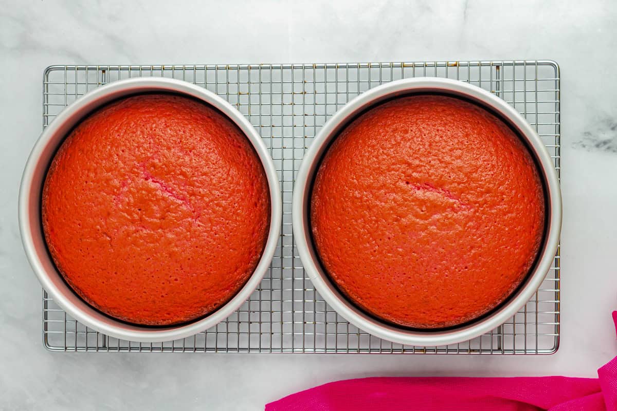 2 baked pink velvet cake layers in round cake pans.