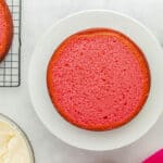 a leveled pink velvet cake layer on a white cake stand.