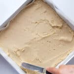 spreading blondie dough in a square baking pan with an offset spatula.