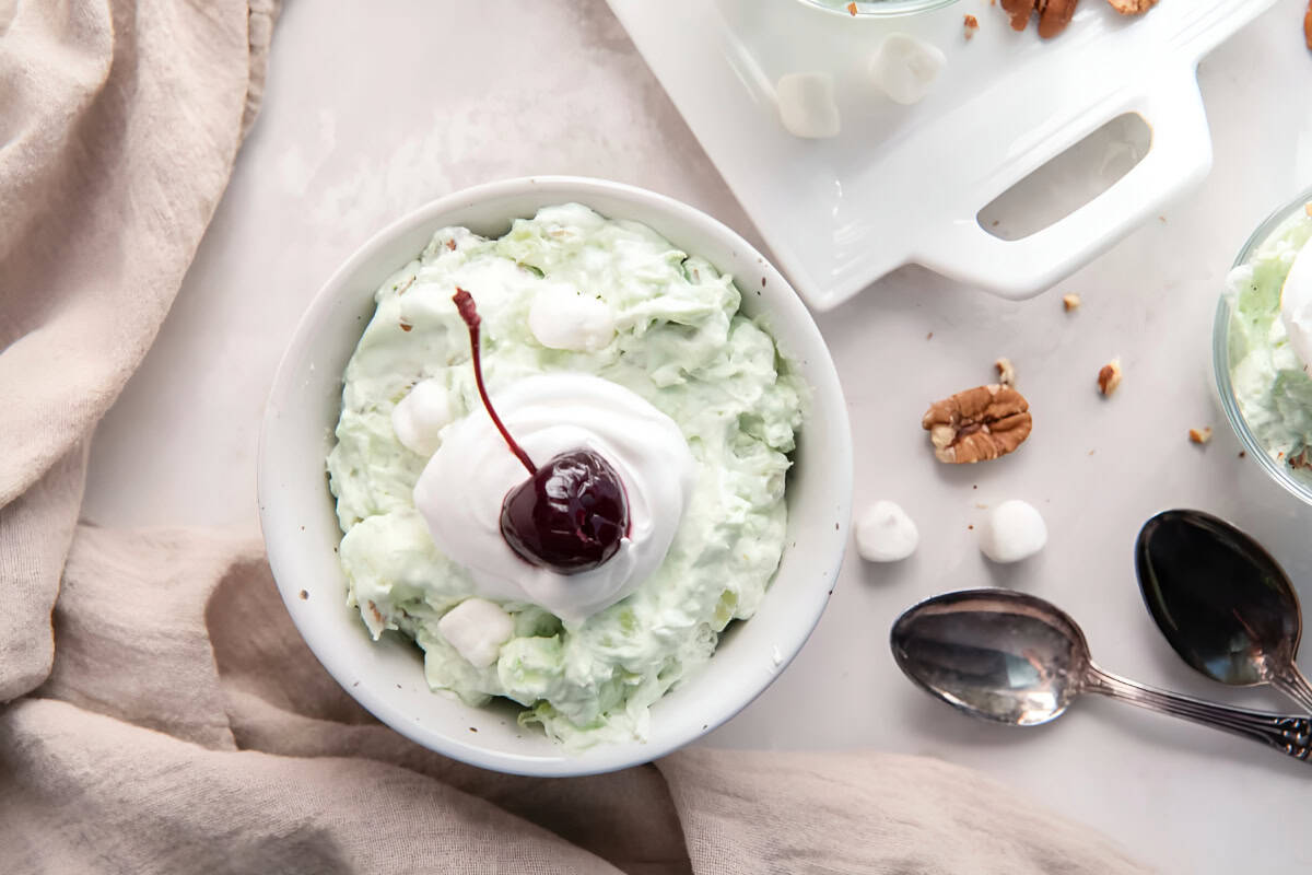 overhead view of a bowl of watergate salad topped with whipped cream and a cherry.