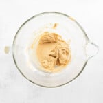 flour added to brown butter peanut butter cookie dough in a glass bowl.