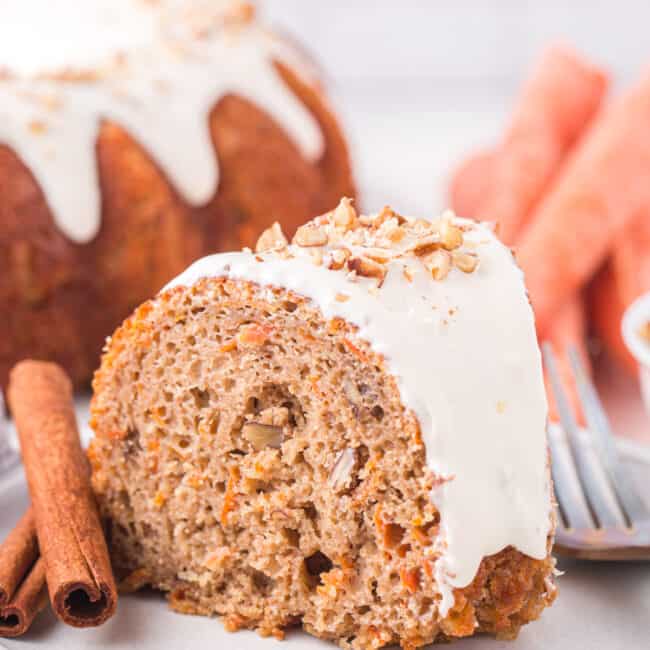 side view of a slice of carrot bundt cake on a white plate with a fork.