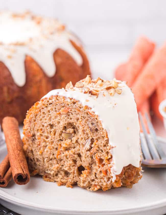 side view of a slice of carrot bundt cake on a white plate with a fork.