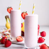 two pink smoothies with strawberries and bananas.