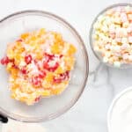 mixed canned fruits in a glass bowl with yogurt and coconut flakes.