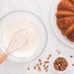 cream cheese frosting for carrot bundt cake in a glass bowl with a whisk.