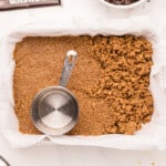 a tray of brown food with a measuring cup.