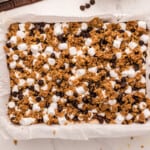 a baking dish filled with granola, chocolate chips and marshmallows.